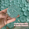 A hand holds a translucent teal squishy bead stress ball with a textured surface.