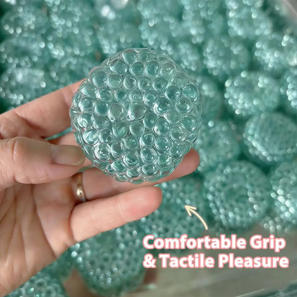 A hand holds a translucent teal squishy bead stress ball with a textured surface.
