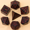 A set of seven fantasy carved polyhedral dice in black and red on a beige surface.