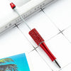 A red beaded ballpoint pen is shown resting on a white surface next to a notebook.