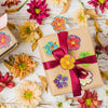 A collection of glitter flower round stickers in various colors scattered on a white wooden surface.