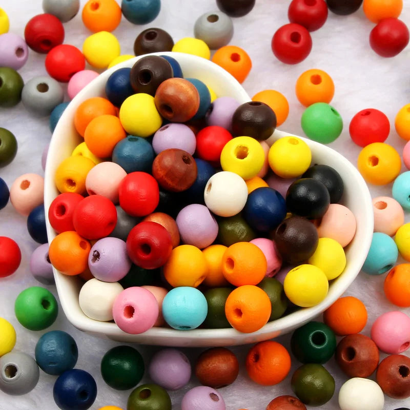 A bowl filled with various natural wooden beads in a wide assortment of colors including red, yellow, green, blue, and brown.