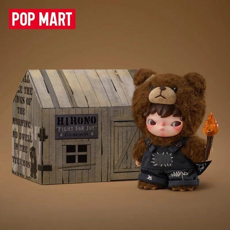 A brown teddy bear plush doll with a face and dark clothing is displayed in front of a wooden box structure.