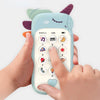 A hand is holding a light blue baby phone toy with purple ears and various buttons.