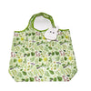 A white pygmy hippo plush toy with a green fabric pouch featuring a floral pattern.