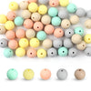 A collection of round silicone beads in various pastel colors including yellow, pink, green, and gray.