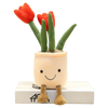 A plush stuffed toy of a tulip succulent with green leaves and an orange flower, sitting on a white box.