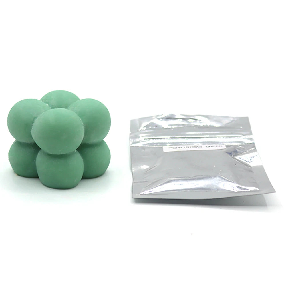 A pile of green candle dye chips for soy wax, beeswax, and paraffin wax.
