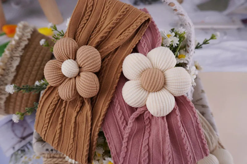 A close-up of floral elastic baby headbands in brown and pink knitted textures.