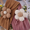 A close-up of floral elastic baby headbands in brown and pink knitted textures.