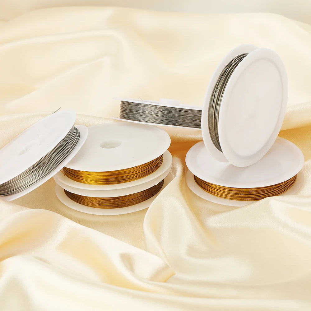 Rolls of stainless steel beading wire and white plastic discs displayed on a cream fabric.