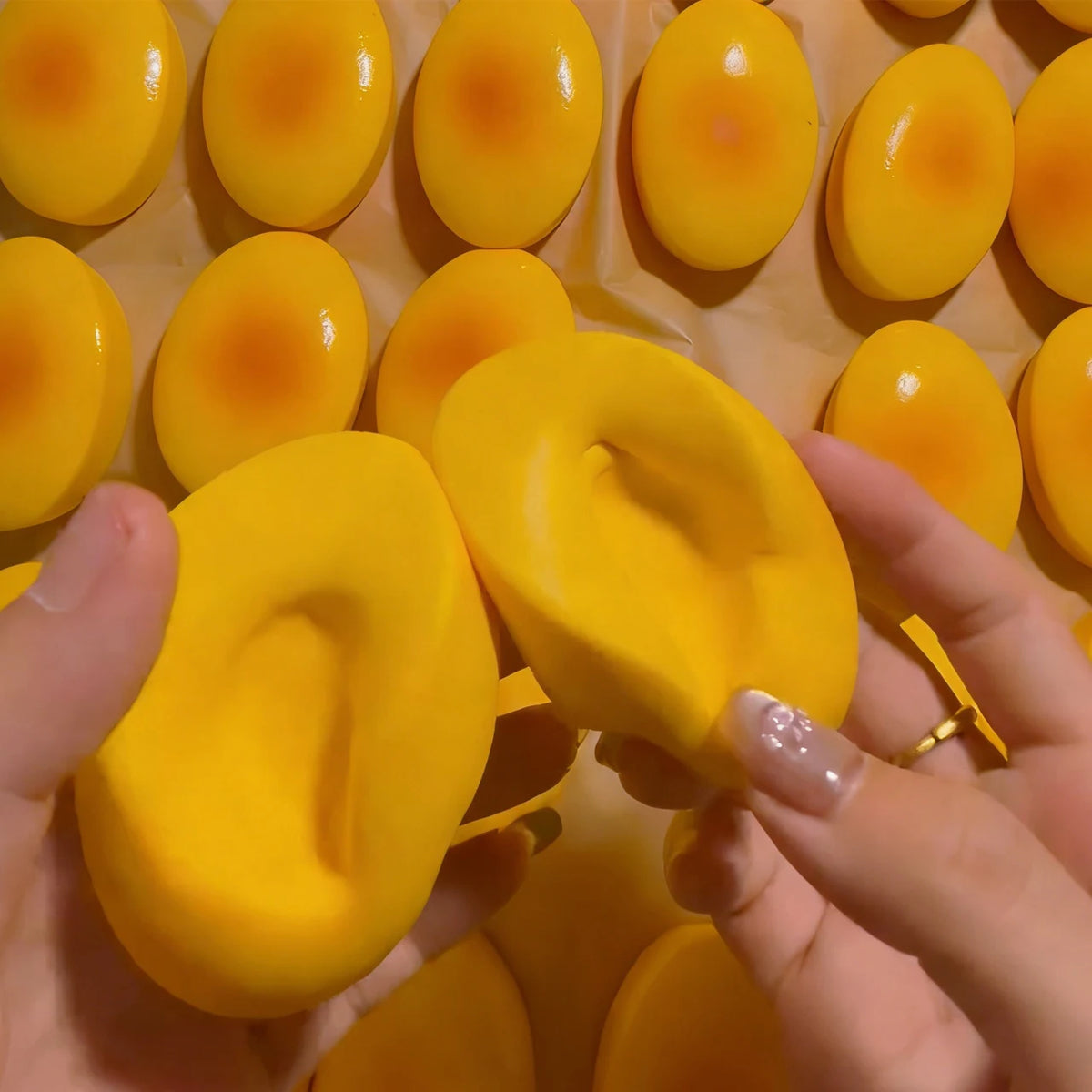 A hand holds a yellow cheese-shaped squishy stress relief toy surrounded by similar toys.