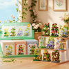 A collection of miniature wooden building sets featuring woodland and windmill themes displayed on a wooden shelf.