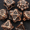 A collection of antique bronze and copper-toned metal dice, including a d10, arranged on a dark background.
