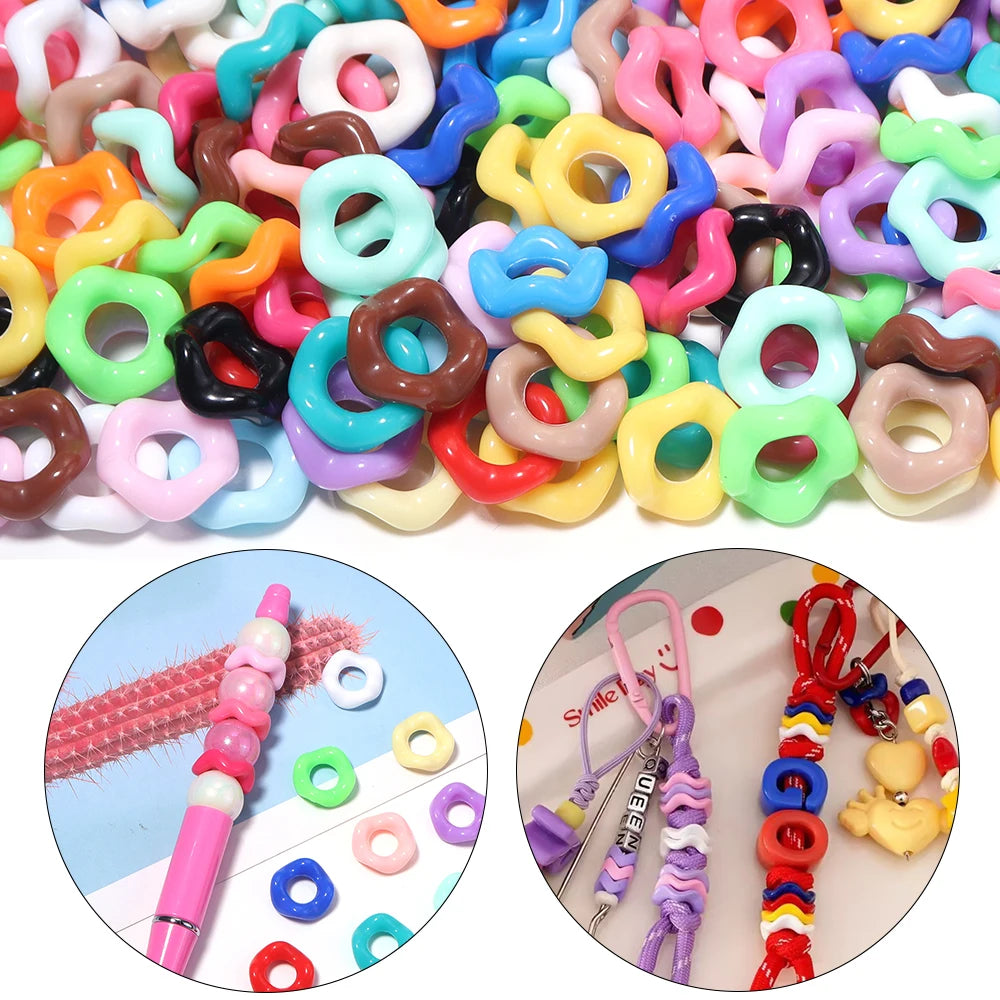 A close-up view of various colorful doughnut acrylic spacer beads for jewelry making, including pink, yellow, green, and purp