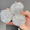 A hand holds three clear, textured squishy beads used for stress relief.