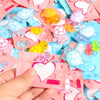 A hand holds a pile of glow in the dark mini turtle collectible figurines blind bags in various pastel colors.