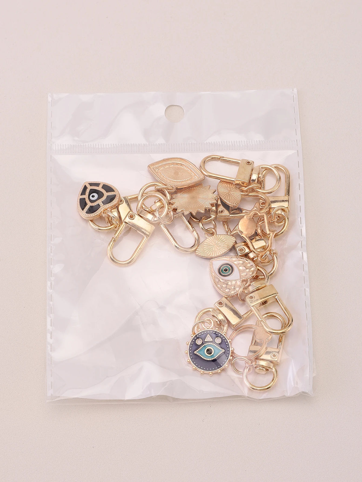 A set of gold-toned cartoon evil eye keychains packaged in a clear plastic bag.