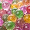 A close-up shot of various colorful glitter bouncy balls in shades of pink, green, yellow, and purple.