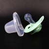 A pair of silicone pacifiers with protective covers are shown against a dark background.