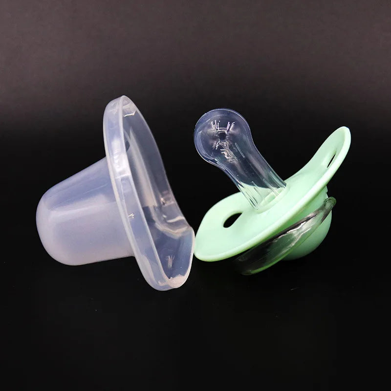A pair of silicone pacifiers with protective covers are shown against a dark background.