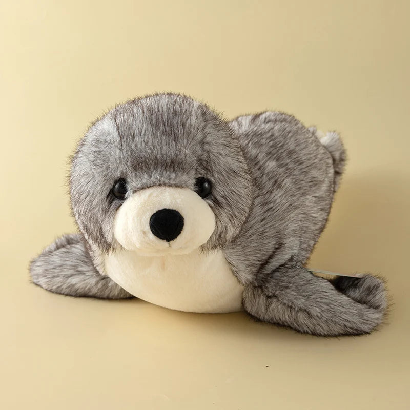 A gray seal plush toy with a black nose and white belly is shown against a light background.