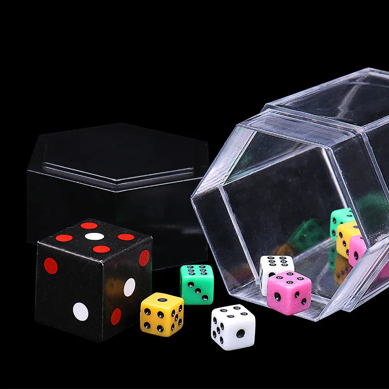 A clear cube box contains various colored and white dice, including red, green, yellow, and pink dice.