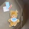 A small, fluffy, light brown Monchhichi plush toy is shown against a neutral background.