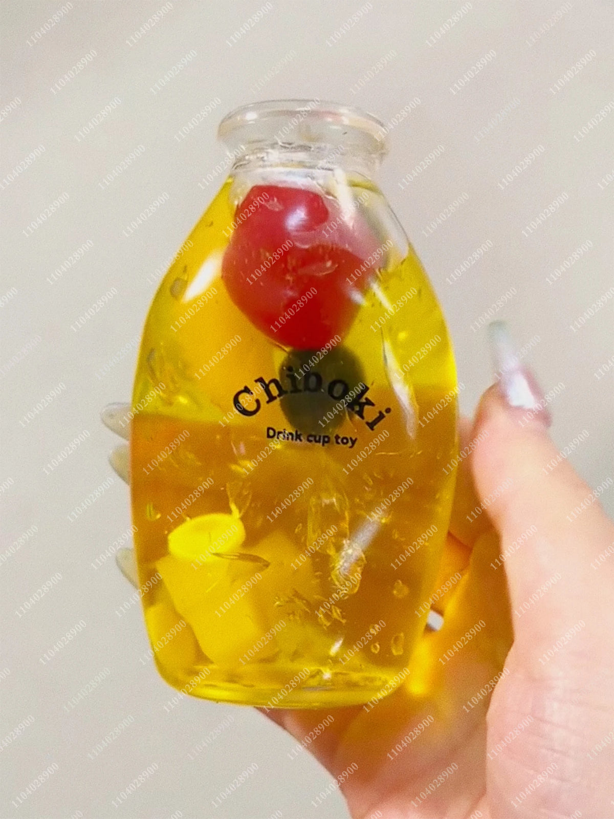 A clear glass bottle filled with yellow liquid and a red object, used as a squishy milk bottle stress ball.