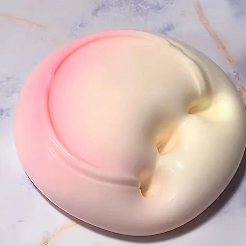 A round, pink silicone stress relief slime is shown on a white surface.