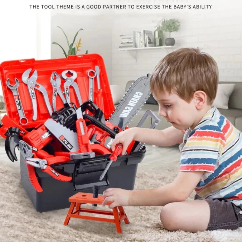 A young boy is using a red and black tool set with an electric drill to practice skills on a floor.