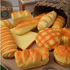A variety of realistic bread squeeze toys in various shapes and colors are displayed on a wooden surface.