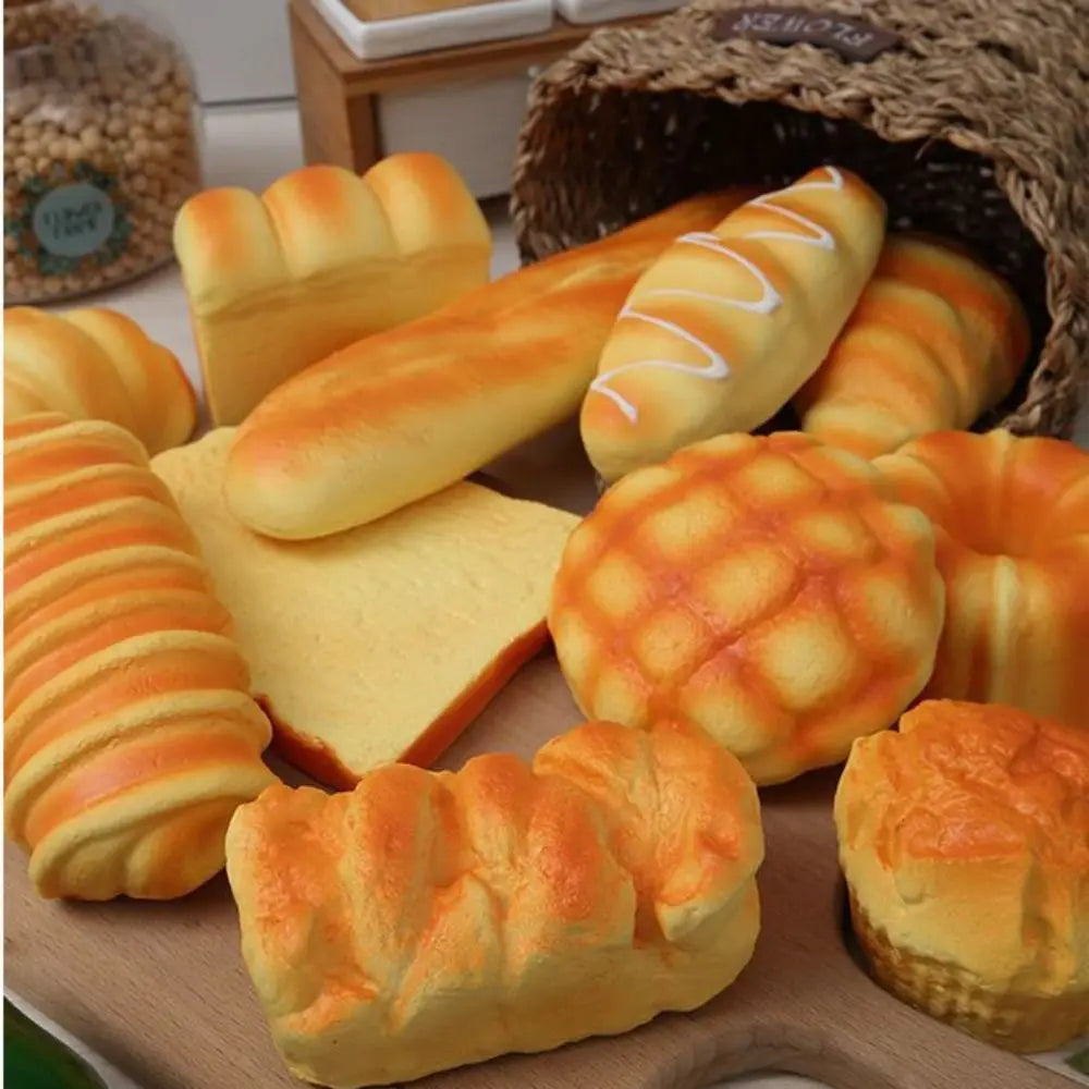 A variety of realistic bread squeeze toys in various shapes and colors are displayed on a wooden surface.