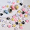 A collection of 50 luminous cat paw nail art charms in various colors and finishes for DIY crafts.