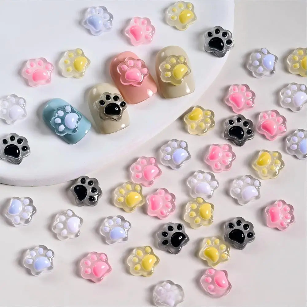 A collection of 50 luminous cat paw nail art charms in various colors and finishes for DIY crafts.