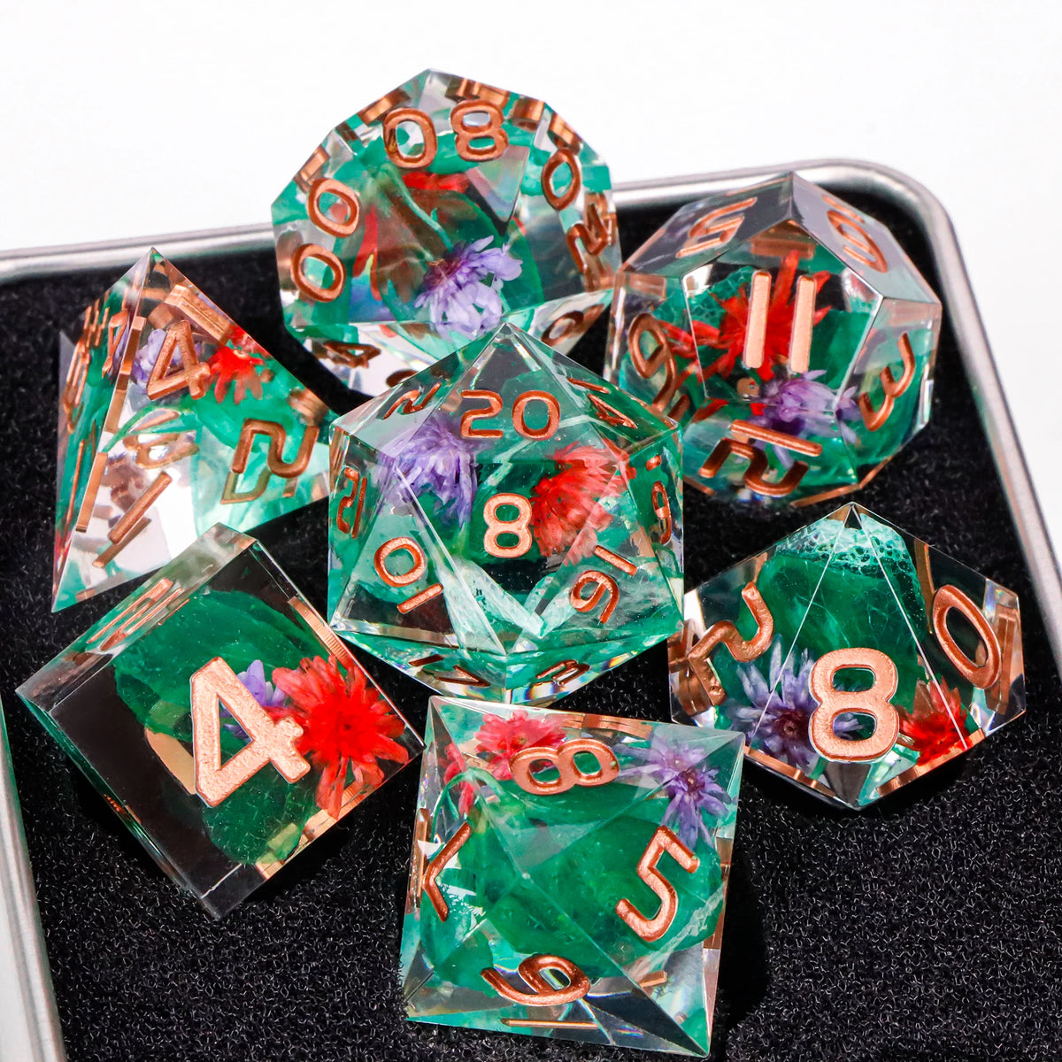 A set of handmade resin sharp edge dice in various colors and shapes resting on a black surface.