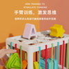 A hand is sorting colorful wooden shapes into a white cube using elastic bands.