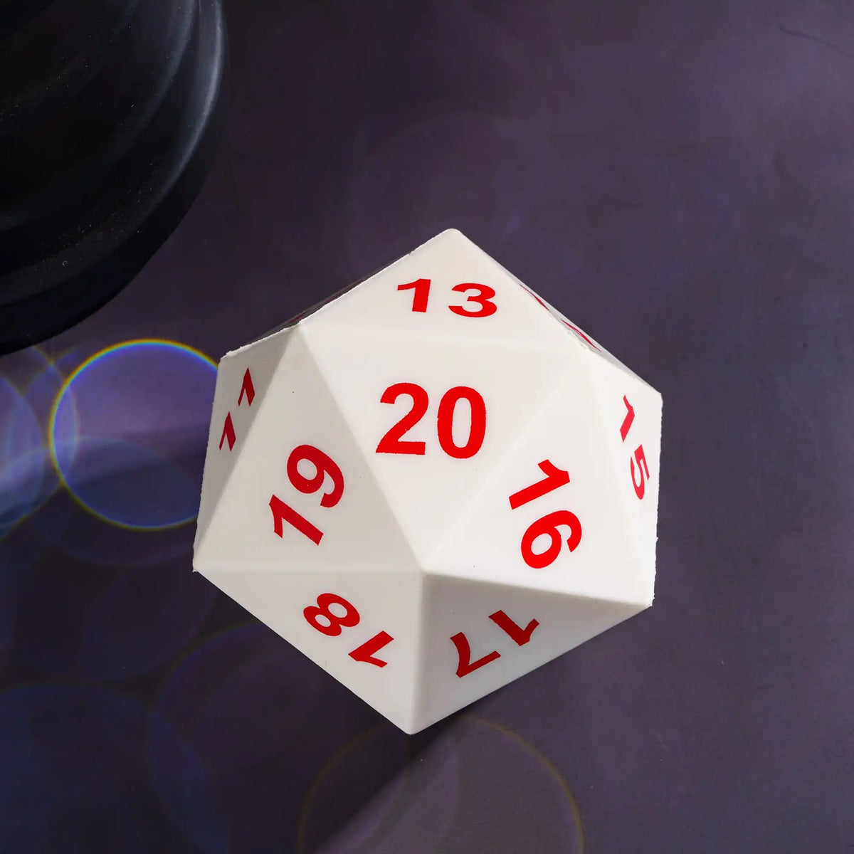 A white D20 polyhedral die showing the number 13 and 20, resting on a dark surface.