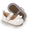 A pair of white leather baby sandals with a gray anti-slip sole and a bow detail.