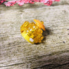 A small, golden-yellow gyro driver for spinning tops resting on weathered wood.