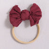 A maroon fabric bow headband with a light beige elastic band.