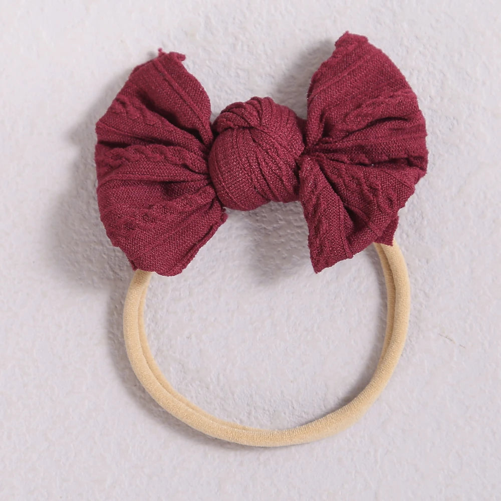 A maroon fabric bow headband with a light beige elastic band.