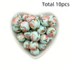 A heart-shaped dish filled with ten pink and green floral printed silicone beads for DIY jewelry making
