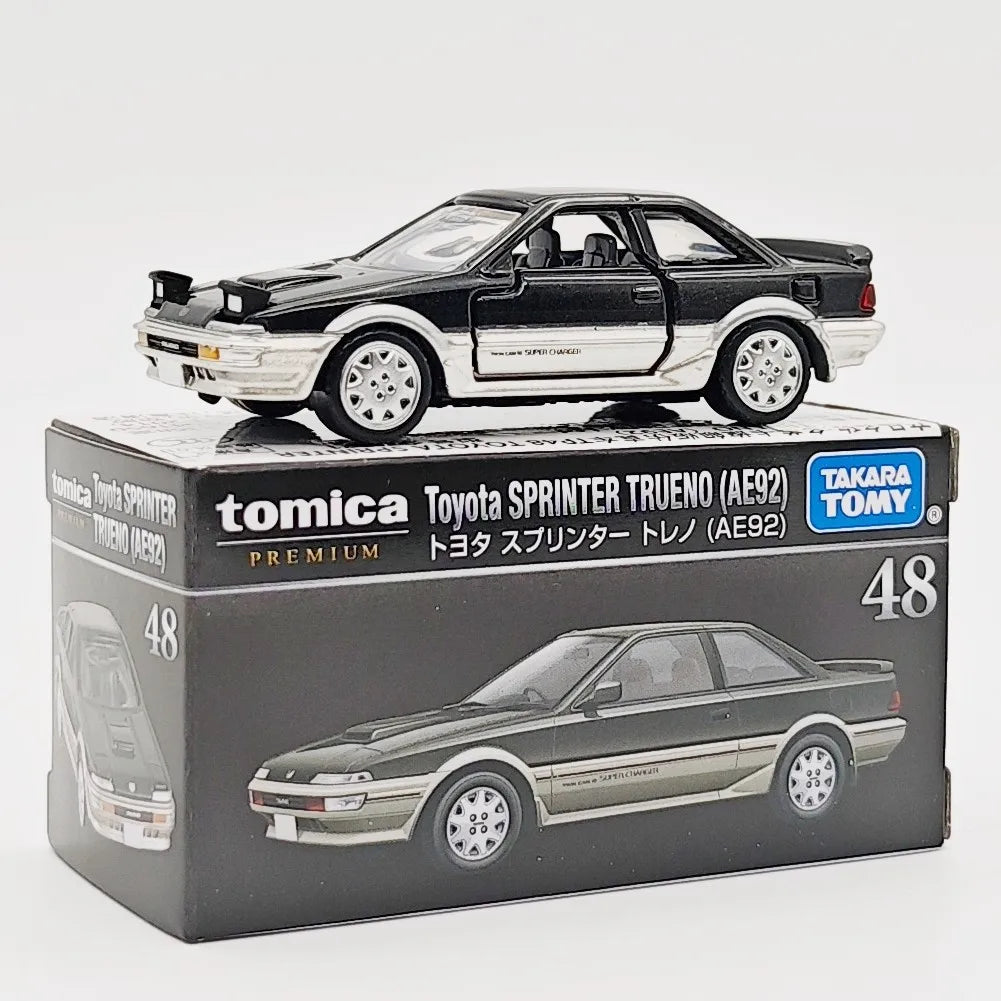 A black Toyota Sprinter Trueno model car in a box, featuring a scale 1:64 die-cast collectible.