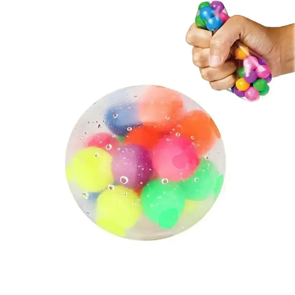 A hand is squeezing a clear ball filled with colorful water beads, some of which are visible on the surface.
