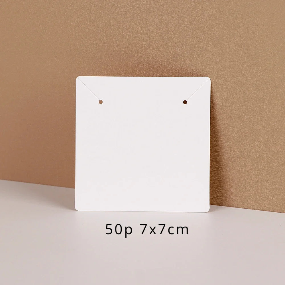 A white square jewelry display card is shown against a beige background, with dimensions listed as 50p 7x7cm.