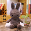 A gray Miffy plush toy with large ears sitting on a wooden surface.