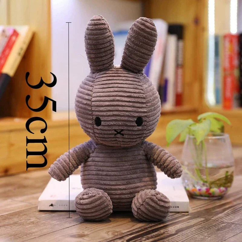 A gray Miffy plush toy with large ears sitting on a wooden surface.