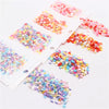 A collection of colorful polymer clay sprinkles in various shades and sizes spread across a white surface.