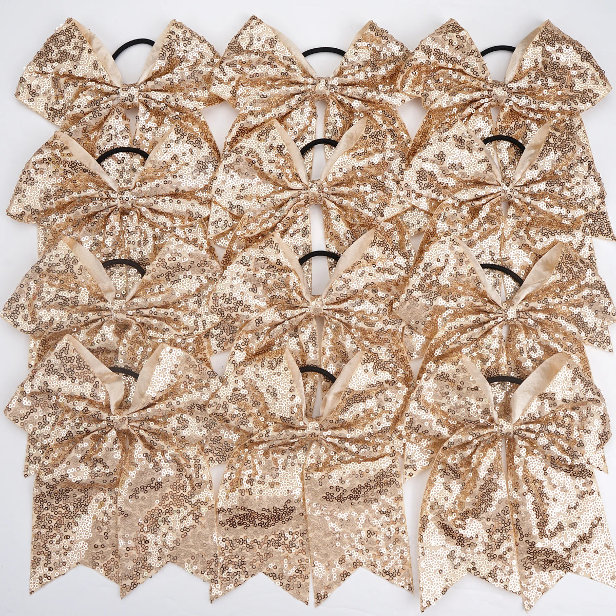 A pack of twelve gold glitter sequin pigtail bows for girls with elastic hair ties.